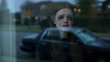 a sad woman crying behind a window
