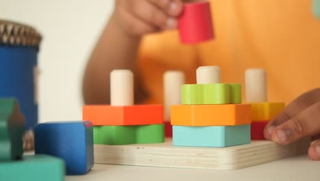 child's hands playing with a colorful wooden stacking toy