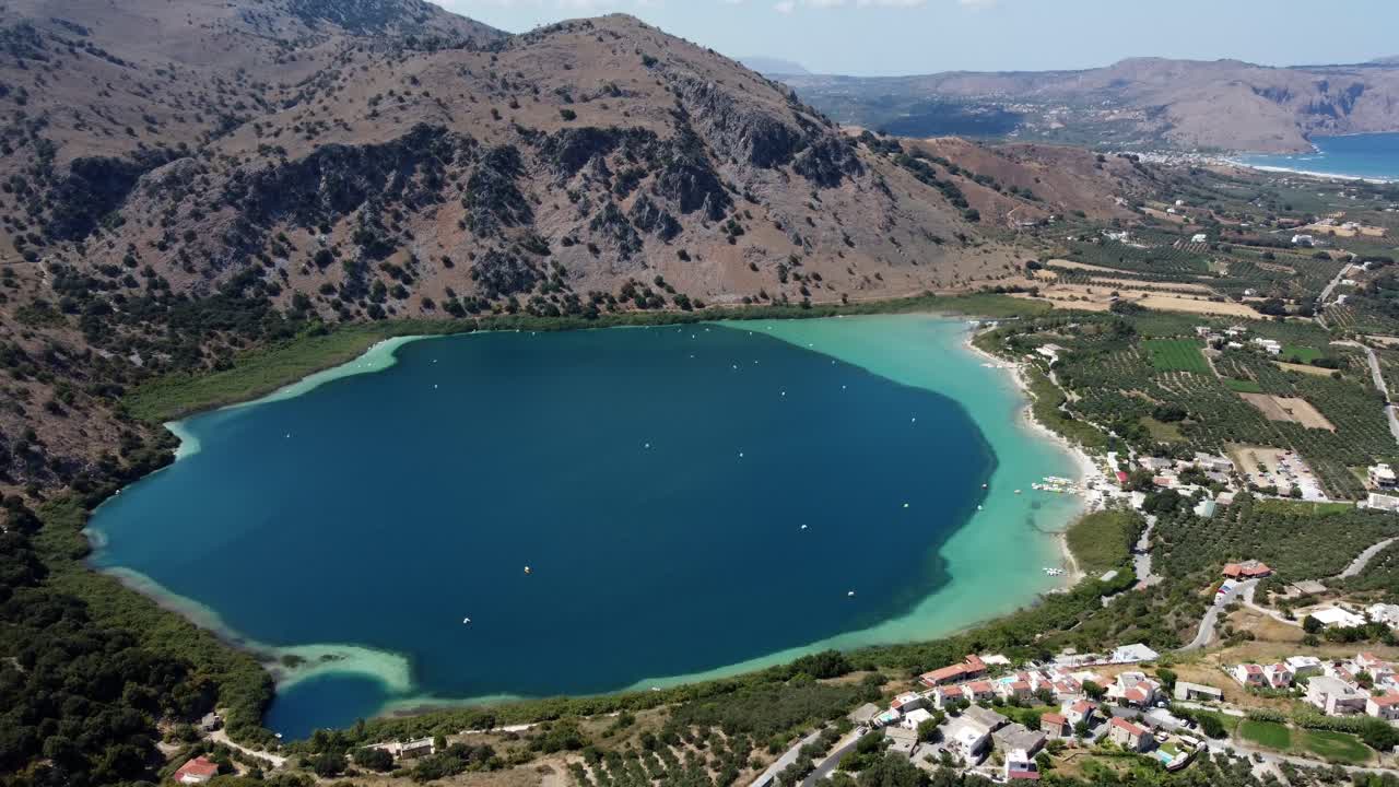 Kournas freshwater turquoise lake in Crete and Kournas mountainous village, Drone shot