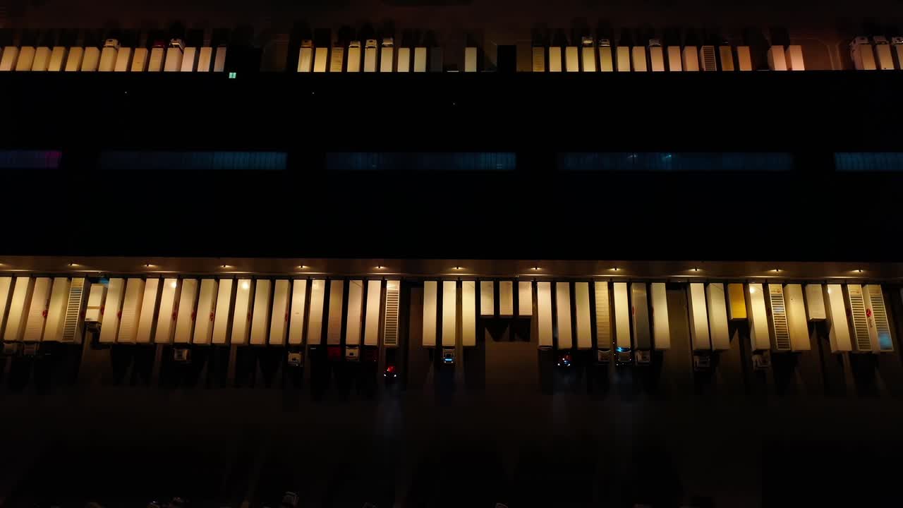 창고가 있는 대형 물류 공원의 공중 전망, 밤에 화물을 내리기 위해 경사로에 서 있는 많은 세미트레일러 트럭이 있는 적재 허브