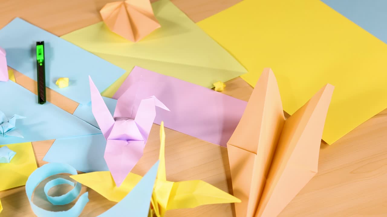 Assorted origami animals and boats arranged on pastel paper sheets, bright lighting, overhead view