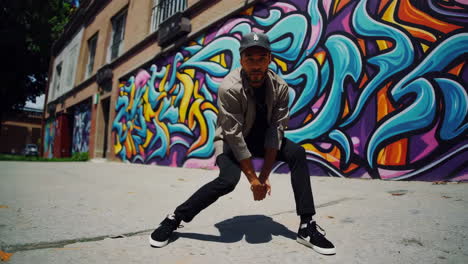 man posing in front of a colorful graffiti wall