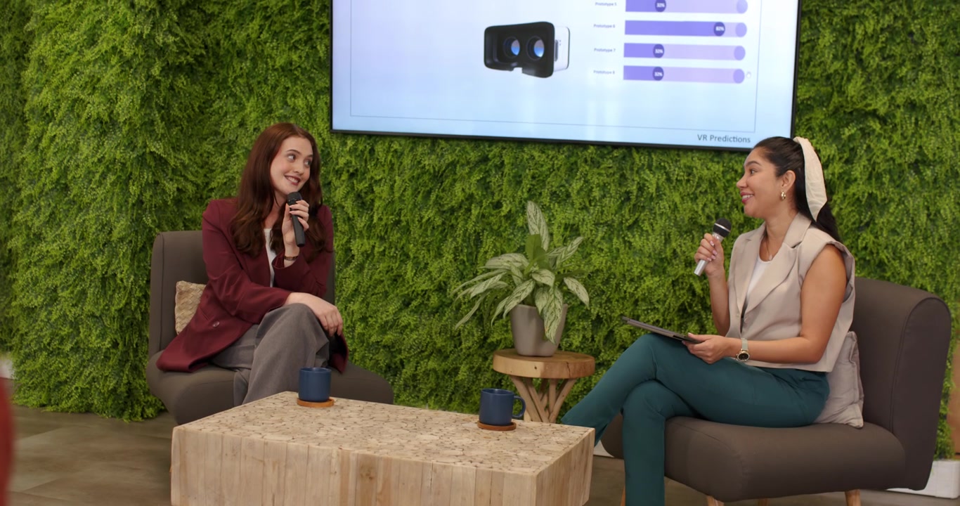 Female host and guest explaining 50% VR slide in studio as camera pulling back, holding mics