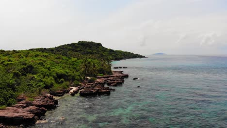 flying low over rocky coast, clear turquoise waters and brightly colored coral reefs, wild tropical island in phu quoc region, vietnam archipel