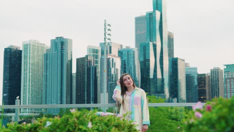 beautiful-caucasian-girl-scratching-head-and-thinking,-Daylight,-outside-in-chicago-Illinois-with-skyscrapers-in-background-and-green-bushes-in-foregrround