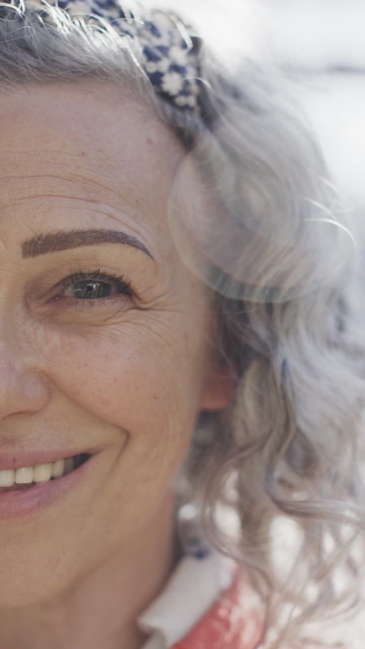 Vertical video portrait of happy senior caucasian woman looking at camera and smiling, slow motion
