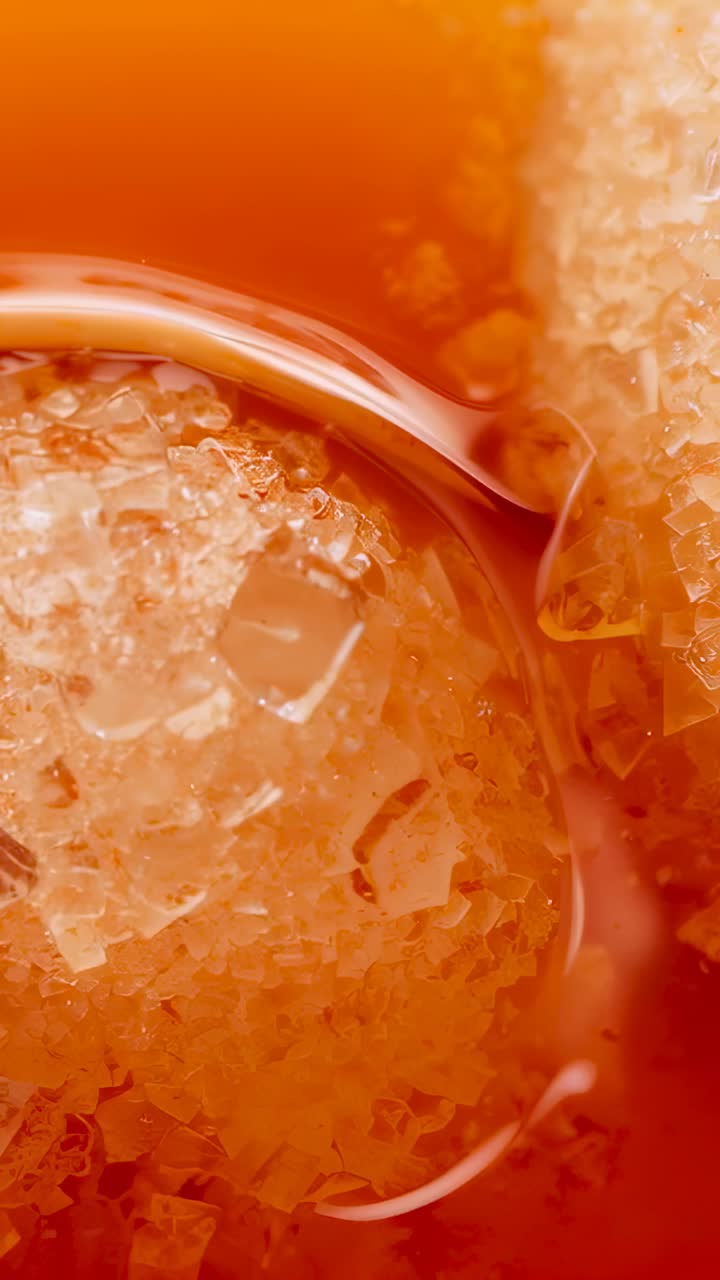 Video verticale: liquido ambrato che spinge un gruppo di cristalli in una capsula macro, formando piccole goccioline