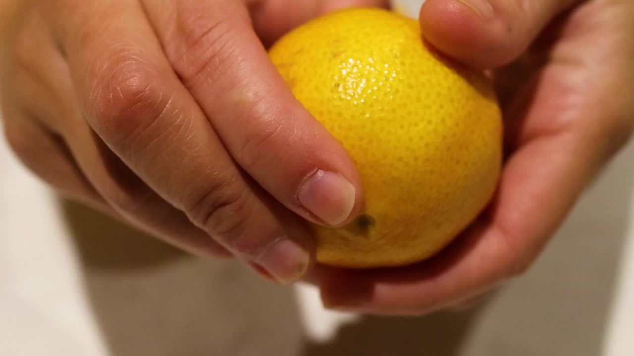 Primer plano detallado de unas manos que pelan con cuidado una naranja madura