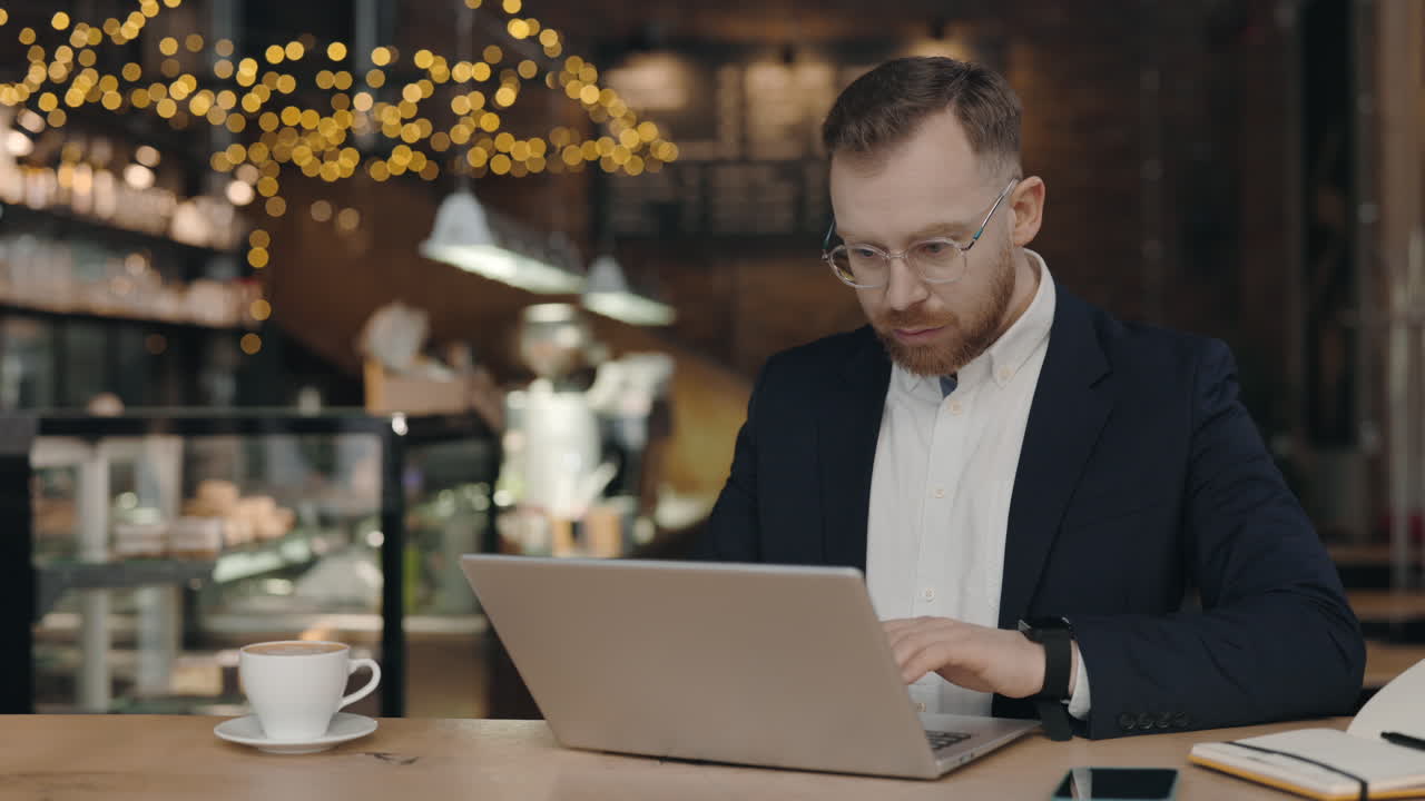 Человек работает на ноутбуке в кафе.