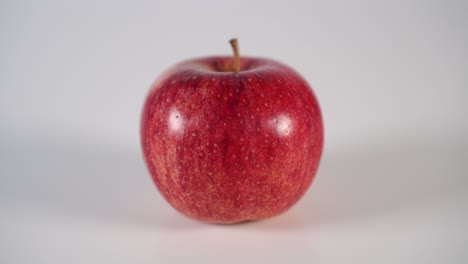 a man sets a ripe red apple on a white table