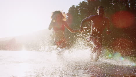 young mixed race couple running and splashing in a lake