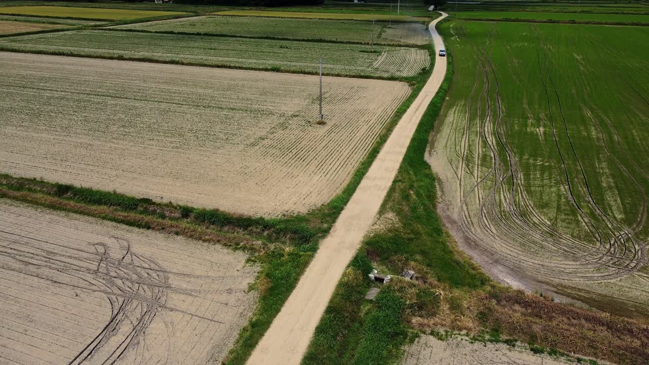 aérea de un camión de recogida que conduce a lo largo de una carretera rural estrecha con tierras de campo agrícolas