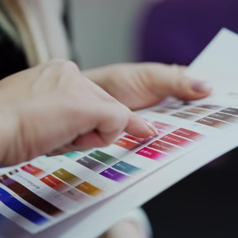 woman choosing the color for her permanent makeup. cosmetologist shows female patient the list of colors for lips tattoo in a beauty salon.