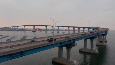 drone rises next to coronado bridge over san diego bay with travelling cars at early morning in california, usa