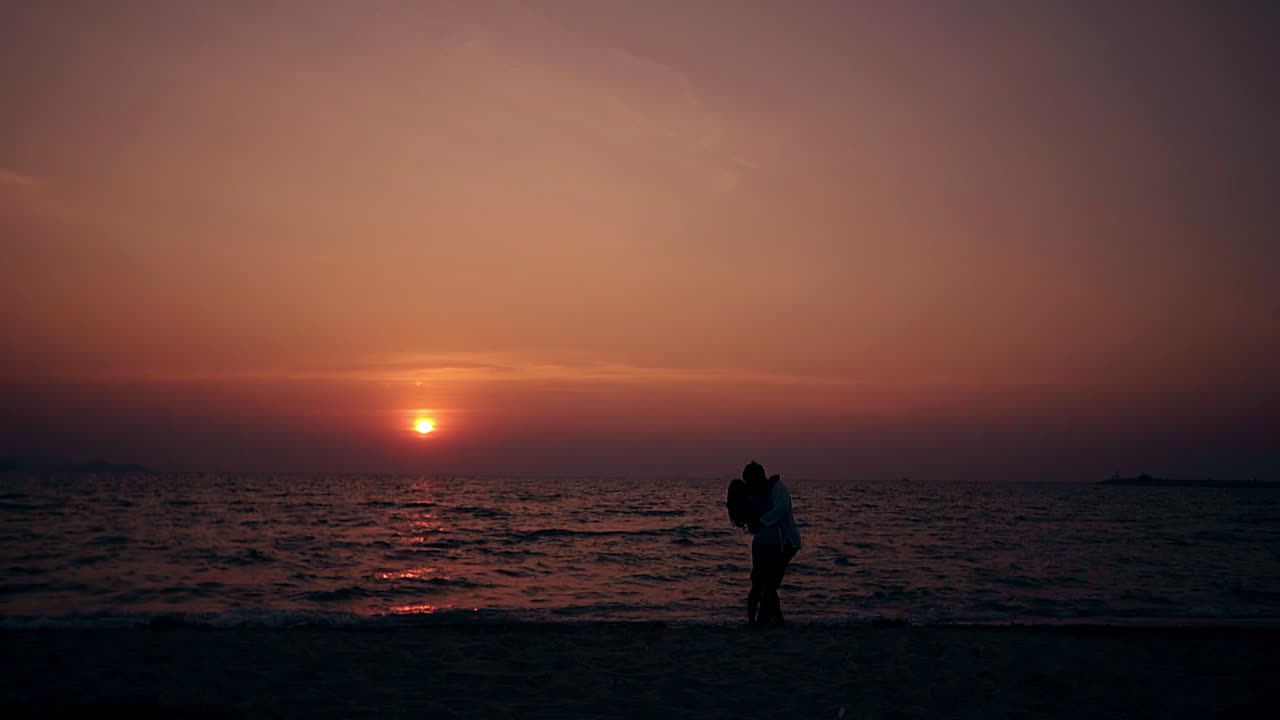 의 포옹과 키스는 비어있는 저녁 해변에서 느린 동작