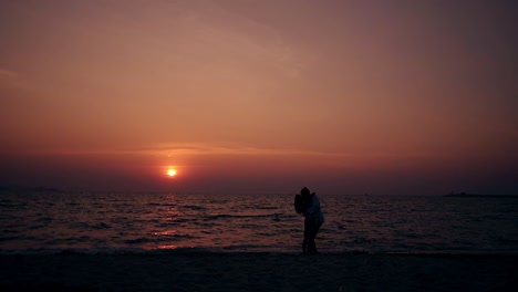 couple-hugs-and-kisses-on-empty-evening-beach-slow-motion