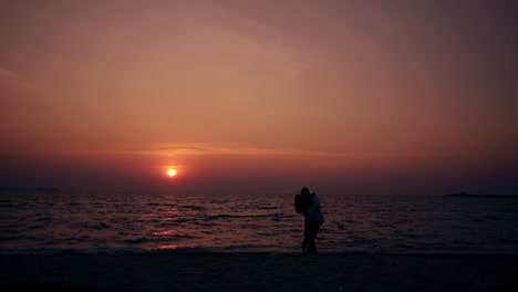 couple hugs and kisses on empty evening beach slow motion