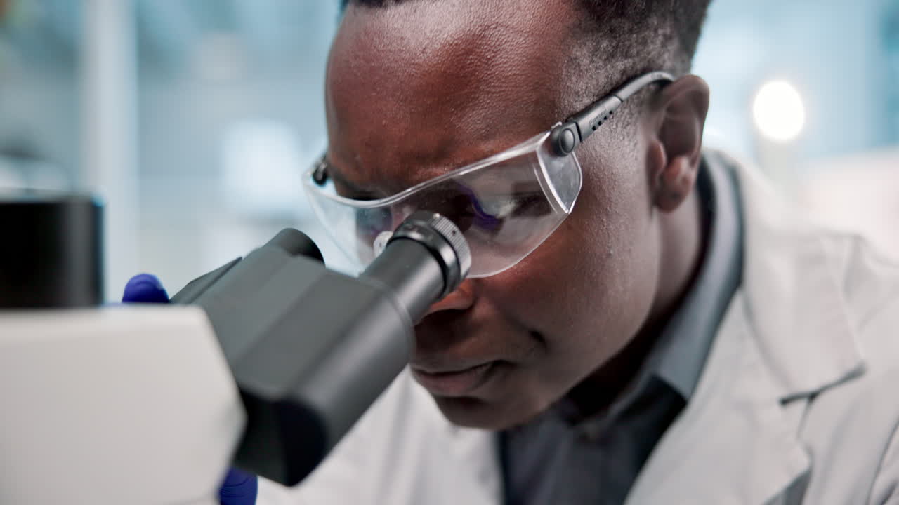 Scientist Examining Sample Under Microscope in Lab