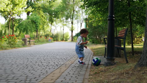 baby boy with a ball in the beautiful green park. child playing outside in summer.