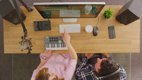 overhead view of male and female musicians at workstation with keyboard and microphone in studio