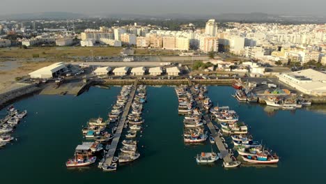 Dock-with-small-fishing-boats-moored-in-the-city-of-Quarteira,-Algarve