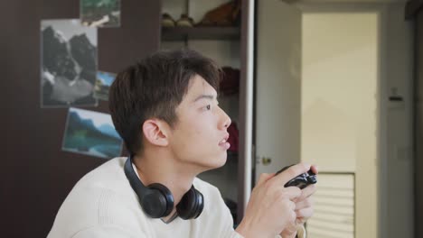 집 에서 소파 에 앉아 비디오 게임 을 하는 아시아 소년