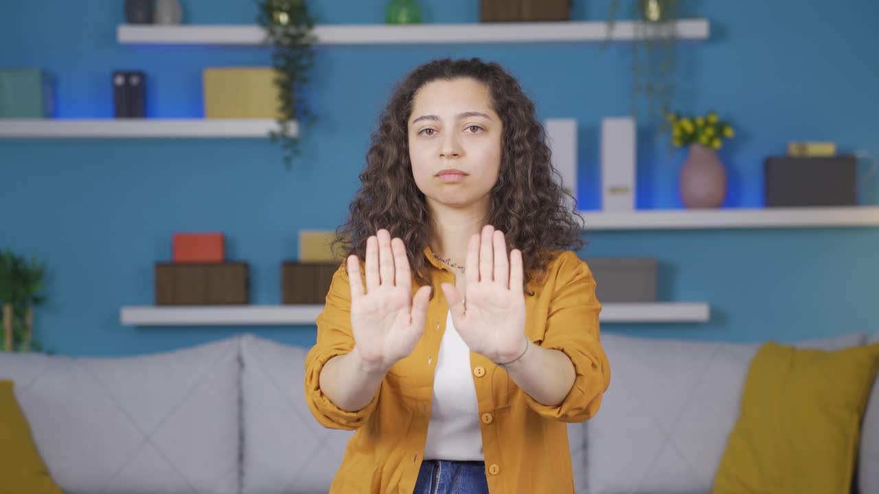 mujer joven haciendo una señal de alto para la cámara.