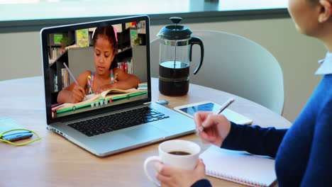 Kaukasische-Lehrerin-Nutzt-Laptop-Bei-Videoanruf-Mit-Schulmädchen-Und-Macht-Sich-Notizen