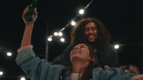 hermosa mujer joven divirtiéndose sentada en un carrito de compras grupo de amigos disfrutando de una loca fiesta en la azotea por la noche celebrando juguetón el fin de semana