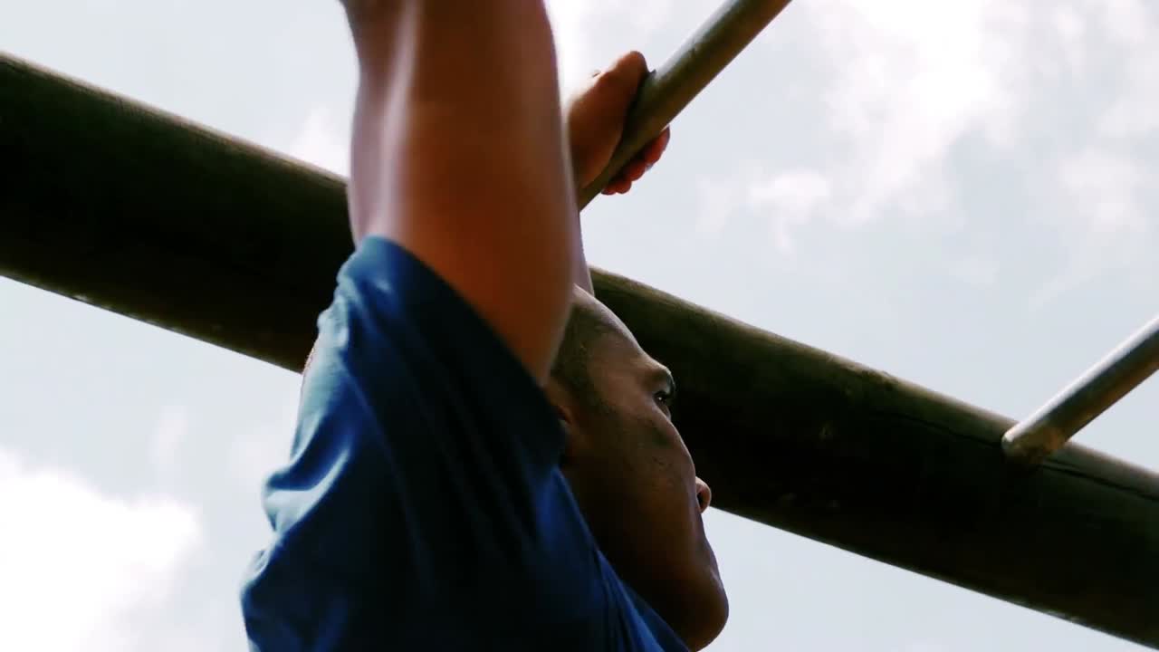 Man crossing the monkey bars during obstacle course