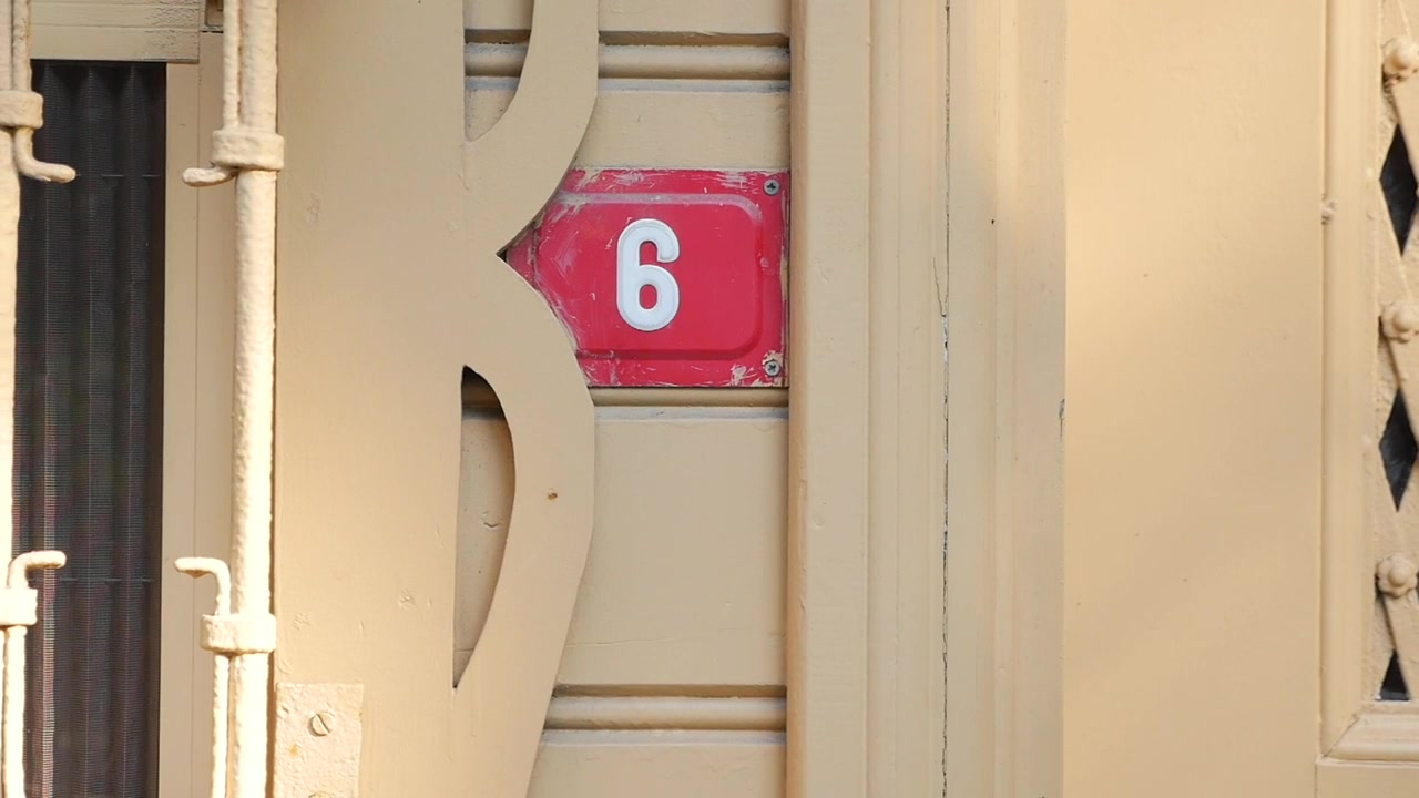 Close-up de uma placa de endereço de casa número seis em uma porta de madeira