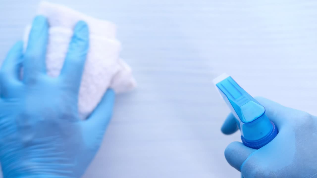 limpieza de una superficie con una botella de pulverización y un paño