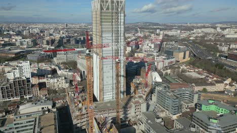 renovation of skyscraper with construction crane and paris cityscape in background