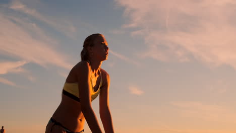 una joven salta y sirve voleibol en la playa en cámara lenta.