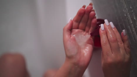 woman pumps shampoo on palm in shower unit closeup. lady pours liquid soap from dispenser in bathroom. woman cleans body with cosmetic product