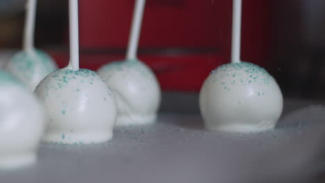 close up of blue edible pastry glitter, falling on white cake pops, slow motion 120fps