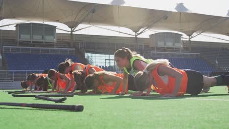 female hockey players doing push-ups on the field