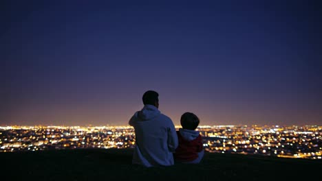 father and son enjoying a night view of the city