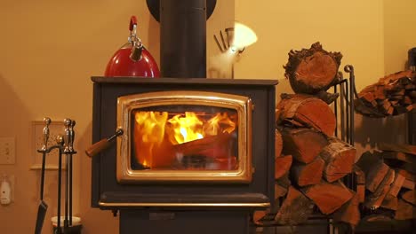 Woodstove-heat-interior-with-logs-near-by-and-kettle-on-top