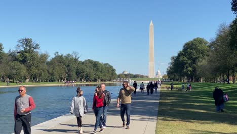 people walk alongside the lincoln memorial reflecting pool in washington dc