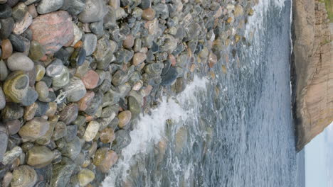 Vertikale-Aufnahme-Von-Wellen,-Die-Entlang-Der-Felsigen-Küste-Des-Norwegischen-Strandes-Krachen