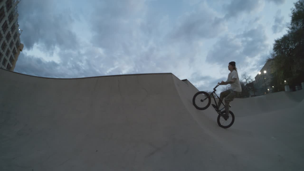 bmx motorista enorme aire fuera de skatepark tazón cuarto de tubo cadera, truco de bicicleta volando en el aire al anochecer en extrema 800fps cámara lenta, 4k ojo de pez