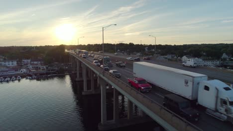 Disparo-De-Un-Dron-Siguiendo-Hacia-Adelante-Sobre-La-Interestatal-En-Un-Puente-Al-Atardecer,-Con-Mucho-Tráfico-En-Hora-Punta-Y-Camiones