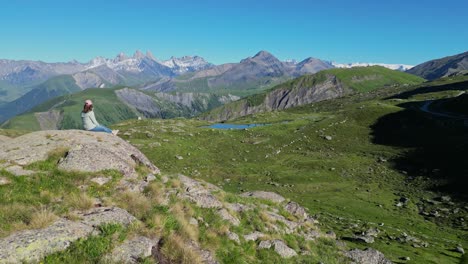 年轻的成年女人坐在岩石上享受法国阿尔卑斯山的全景 - 空中