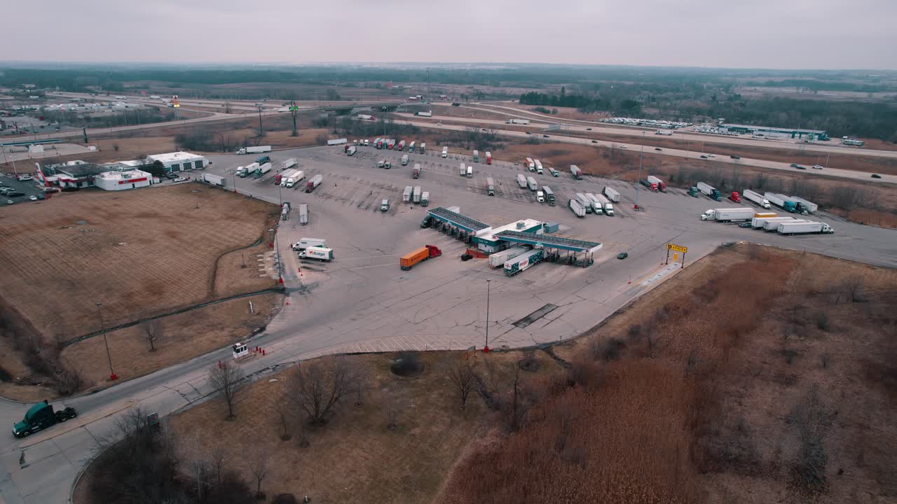 красный полугрузовик и оранжевые прицепы въезжают на станцию топливного насоса, чтобы пополнить топливный бак