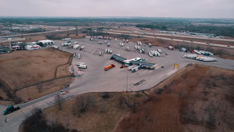 red semi truck and orange trailers enters fuel pump station to refill fuel tank