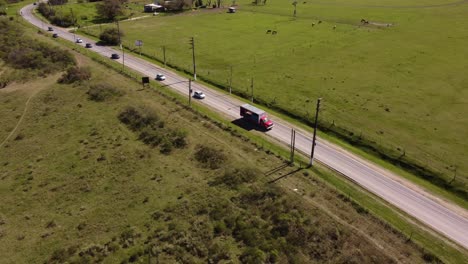 Aerial-view-of-a-red-cargo-truck-driving-by-road-in-rural-area-of-Buenos-Aires,-Argentina