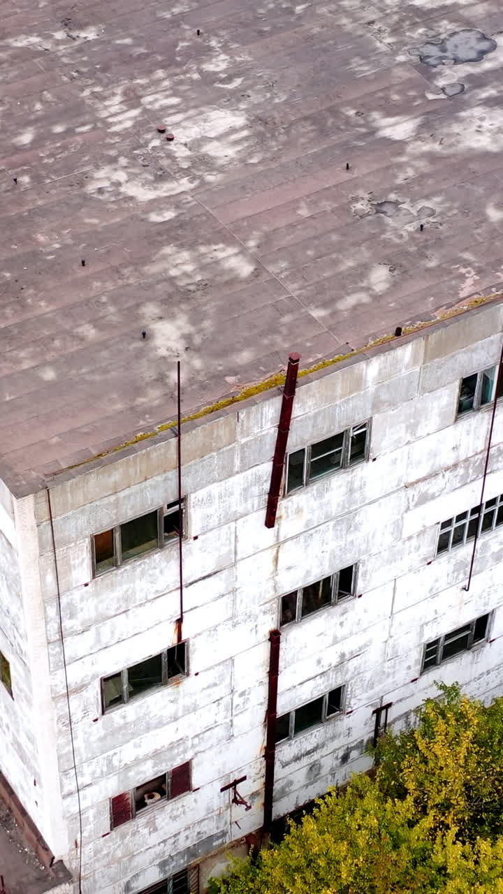 Old factory. Abandoned buildings and warehouses with broken windows after the war. Empty industrial plant. View from above.. Vertical video