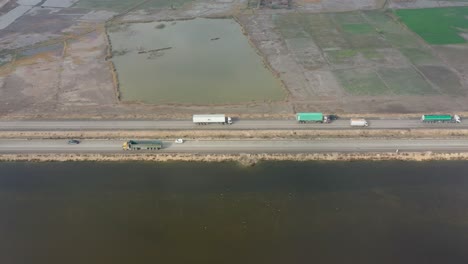 vista aérea de camiones y camiones cisterna que viajan a lo largo de la carretera pasando por tierras agrícolas en sindh
