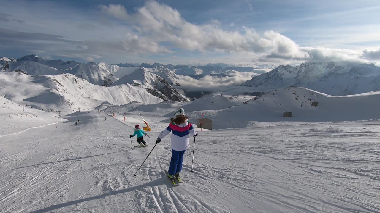 Kids skiing great turns high up in the mountains with with insane mountain view